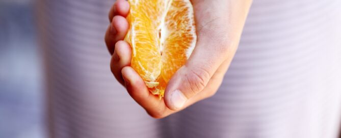 selective focus photography of person squeezing orange fruit